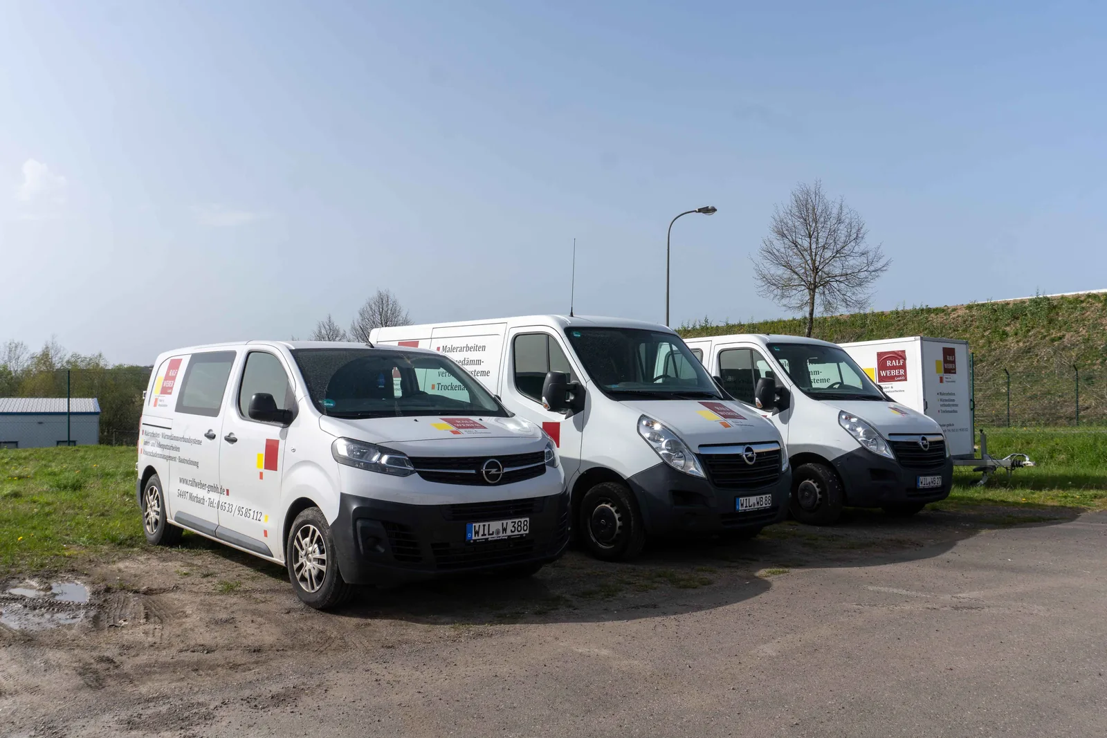 Mehrere weiße Firmenwagen der Ralf Weber GmbH stehen nebeneinander vor dem Betrieb