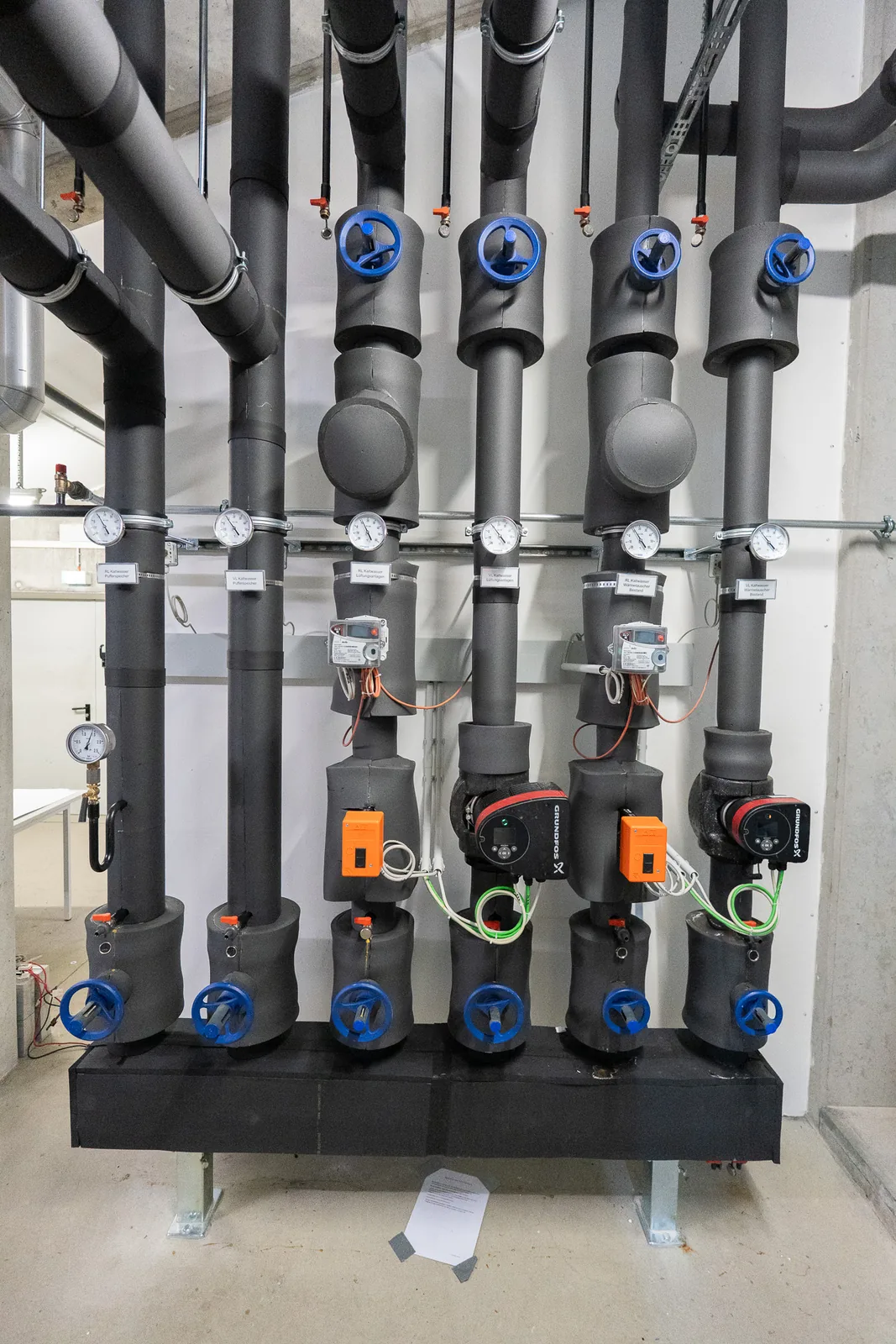 Neu installierter Heizungsverteiler mit Pumpen, blauen Ventilen und gedämmten Rohren im Technikraum, umgesetzt von Christ Heizung und Sanitär