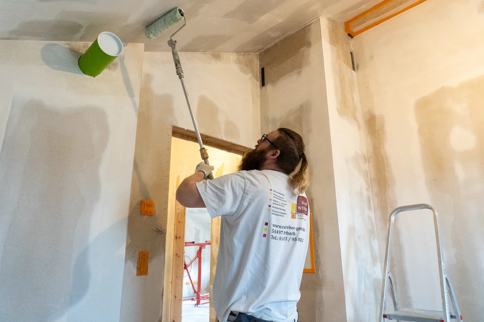 Maler der Ralf Weber GmbH streicht mit der Farbrolle eine Wand im Neubau