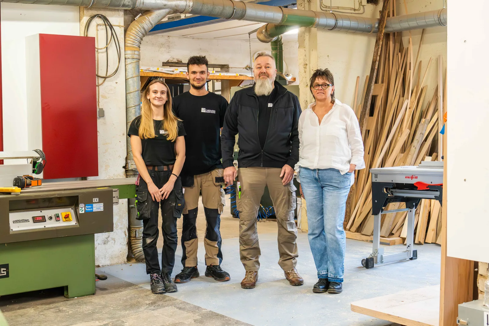 Team der Schreinerei Zimmer-Blasius steht gemeinsam in der Werkstatt vor einer Maschine