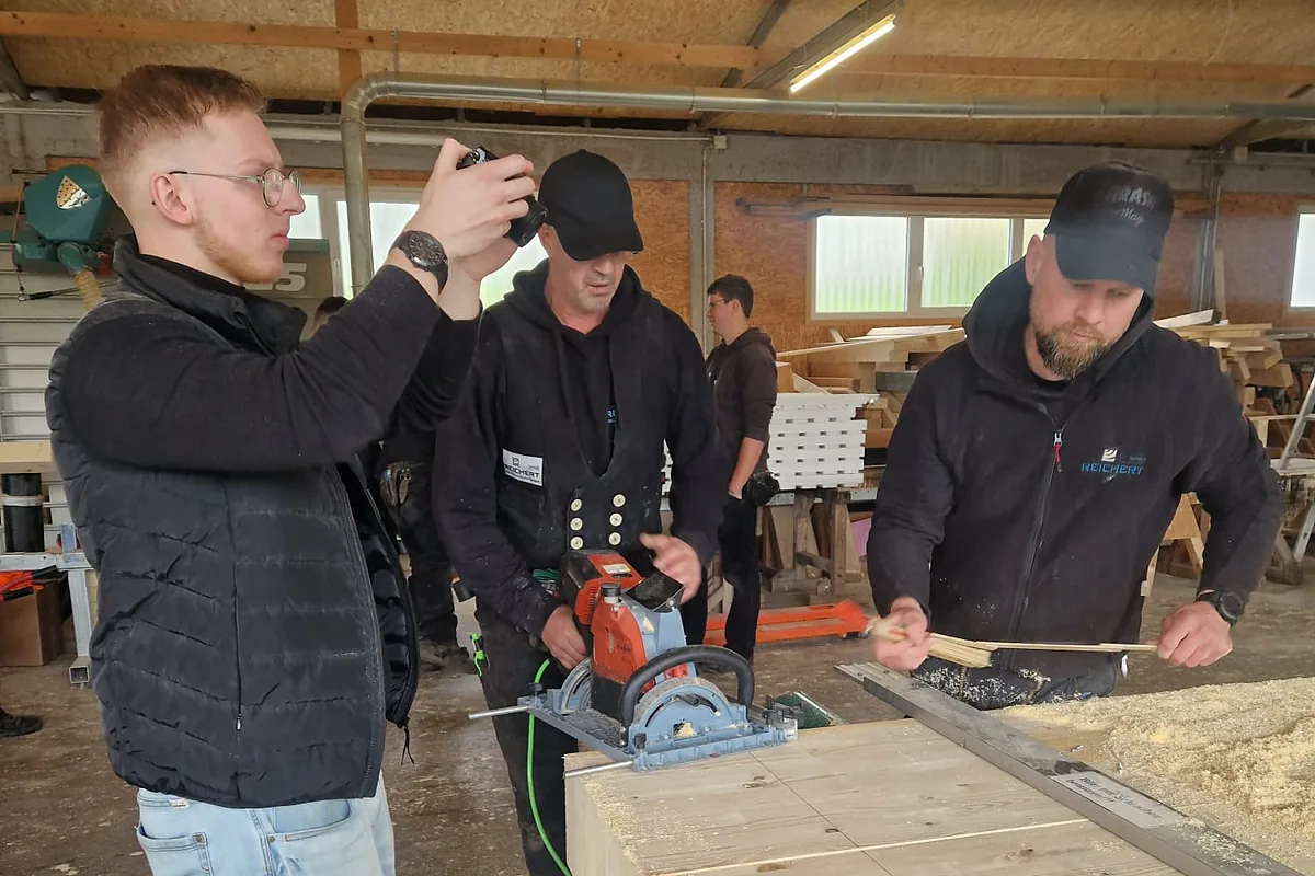 Fabian Bohr filmt zwei Zimmerer der Reichert GmbH beim Sägen mit der Handkreissäge in der Halle